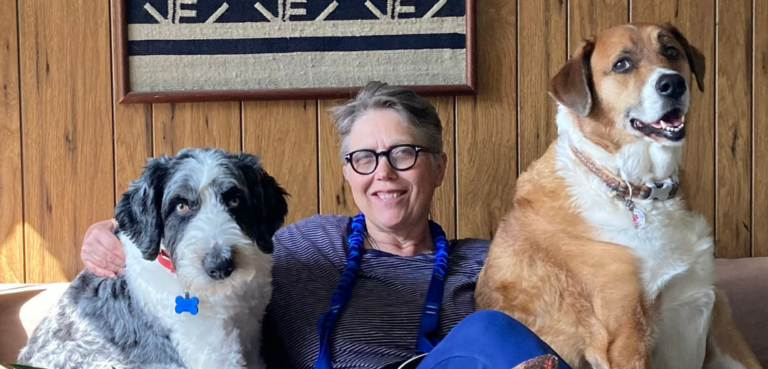 Sarah Bullen sits on a couch with her two dogs.