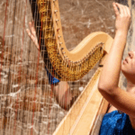 Zoé Buyck playing a harp with a marble wall in the background