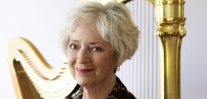 Erica Goodman stands in front of a harp with a gilded column