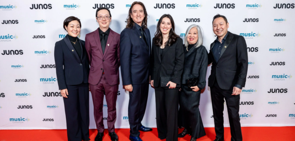 Kimikos-Pearl_2026-JUNO-Awards_pc_CARAS_Vito-Amati Performers, composer, and producers of Kimiko’s Pearl smile while standing on the orange carpet at the 2026 JUNO Awards Gala