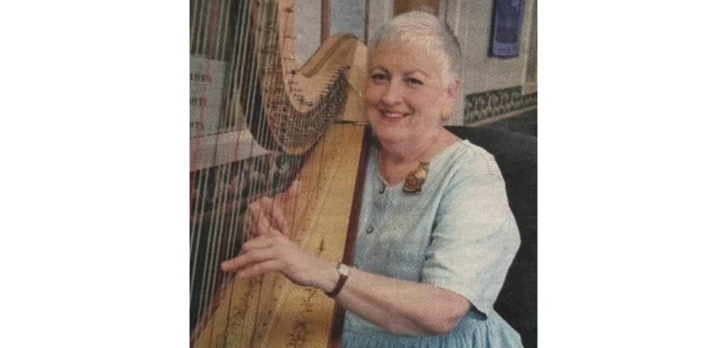 Laurie Buchanan poses with a smile with her hands ready to play her harp