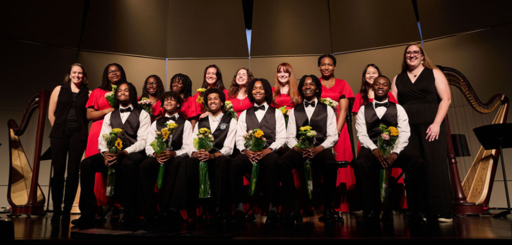 UYHE_spring-concert-2026_GenesisFoundationAward-recipient Urban Youth Harp Ensemble members and instructors pictured onstage holding bouquets after the ensemble’s spring 2026 concert