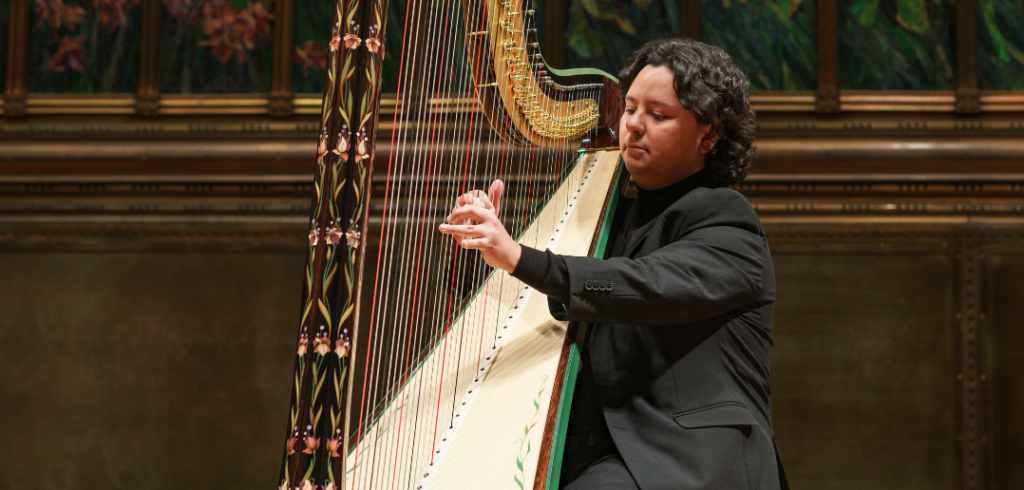 Emmanuel Padilla Holguín playing the harp, wearing a black suit