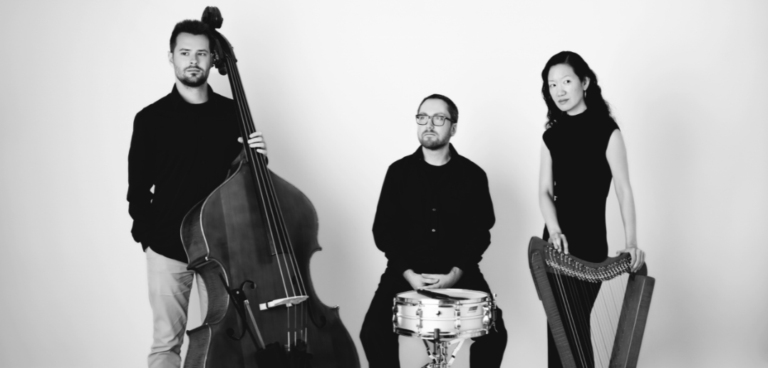 Rock_City_Falls_Trio_l-to-r-Handron-Forman-Chang_pc_Jessica-Tomaselli A black-and-white photo of the Rock City Falls trio members standing with their instruments against a white background