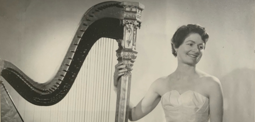 Black-and-white image of Sheila Larchet Cuthbert with her hand on an Erard harp